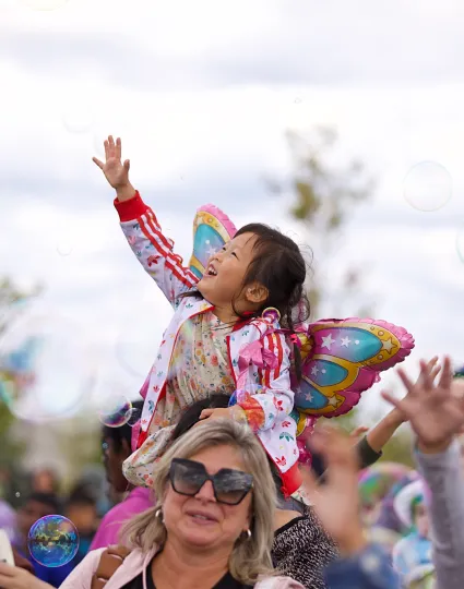 Child playing with bubbles at event.