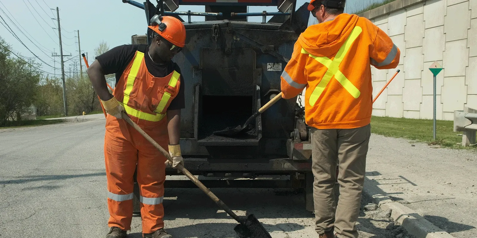 2 Markham employees filling a pot hole.